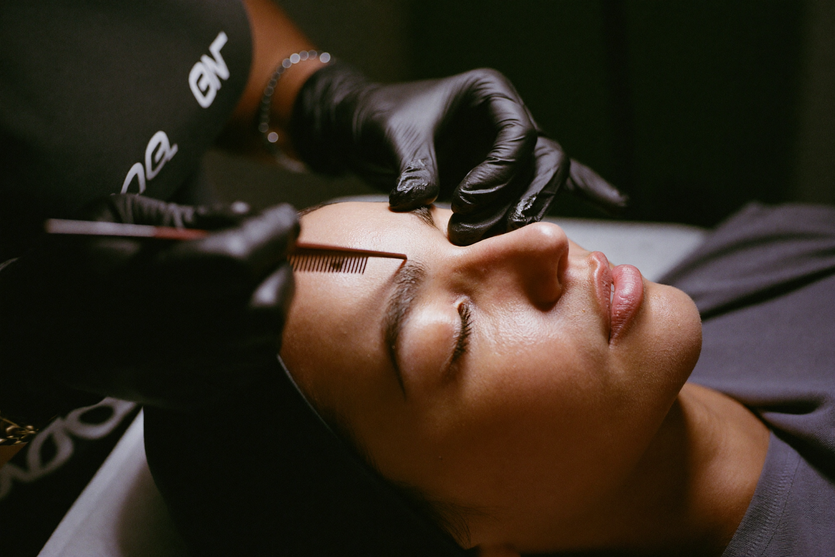Brow artist combing brow hairs upward during brow lamination